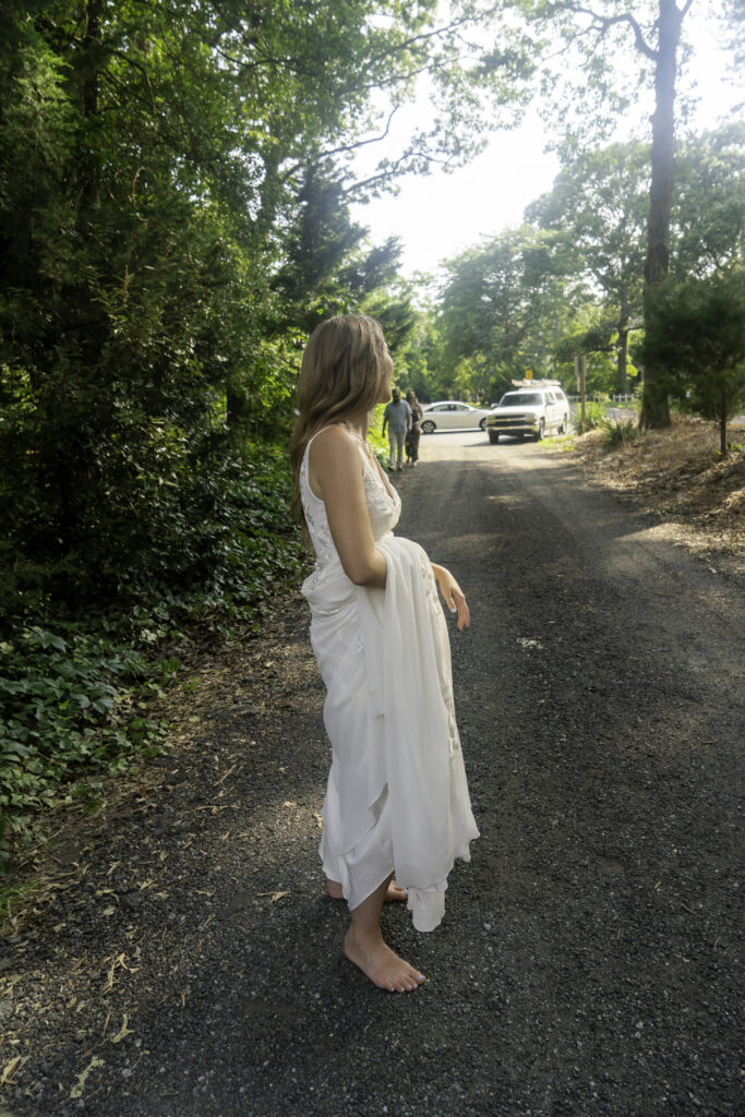 a woman in a white dress standing on a road