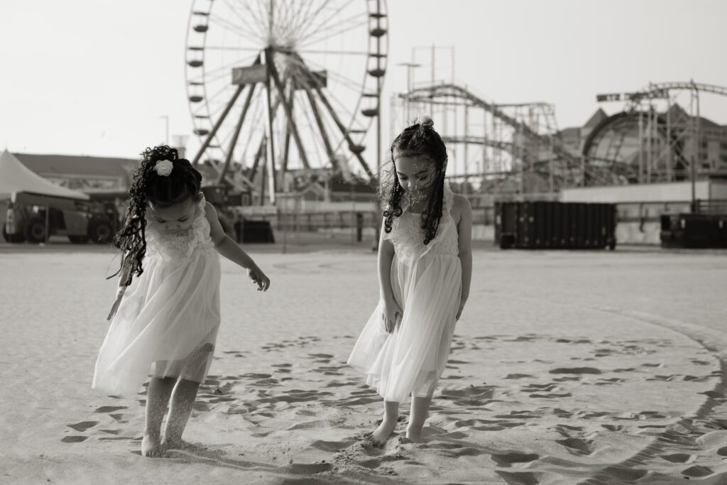 two young girls in white dresses are walking on the beach
