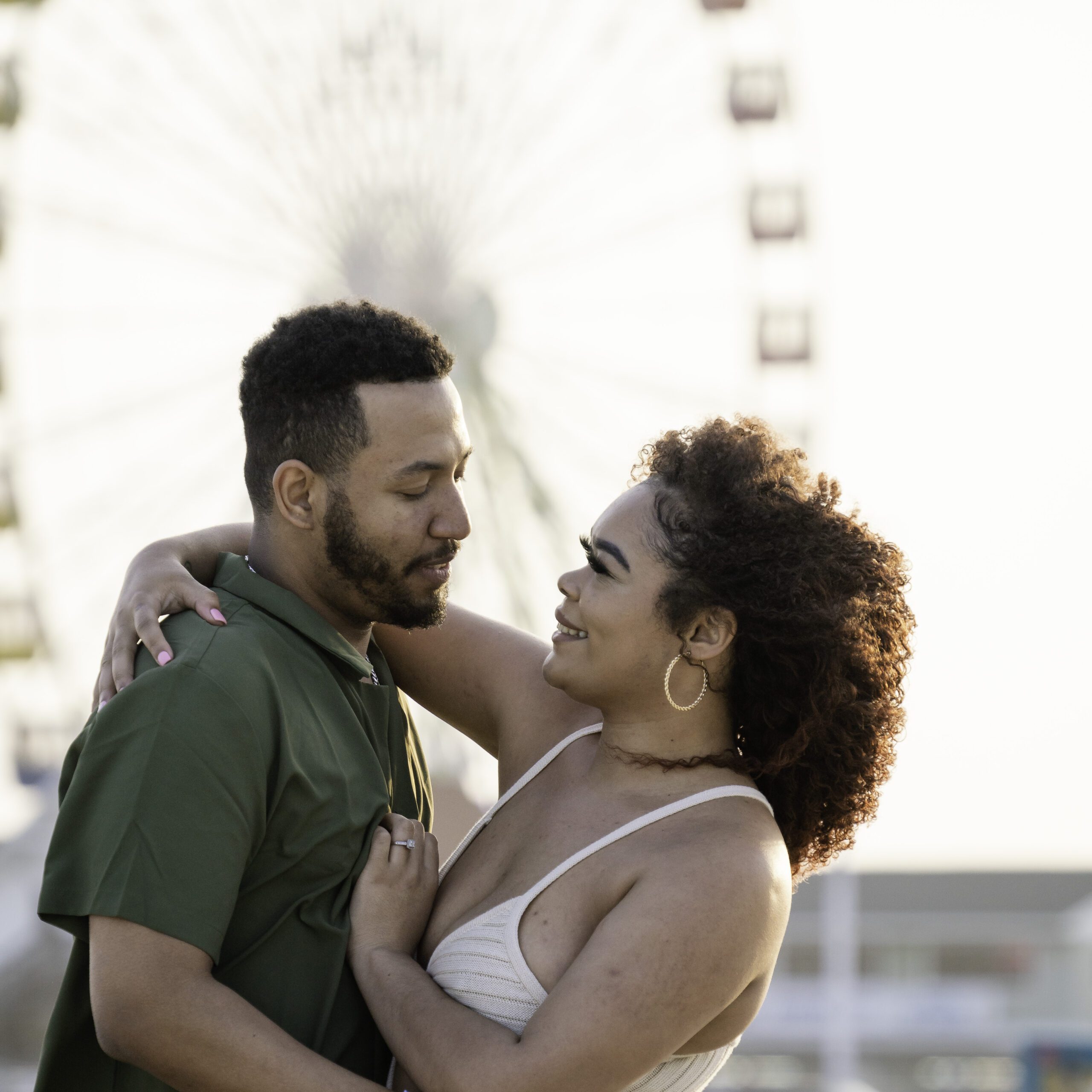a man and woman embracing in front of a ferris wheel