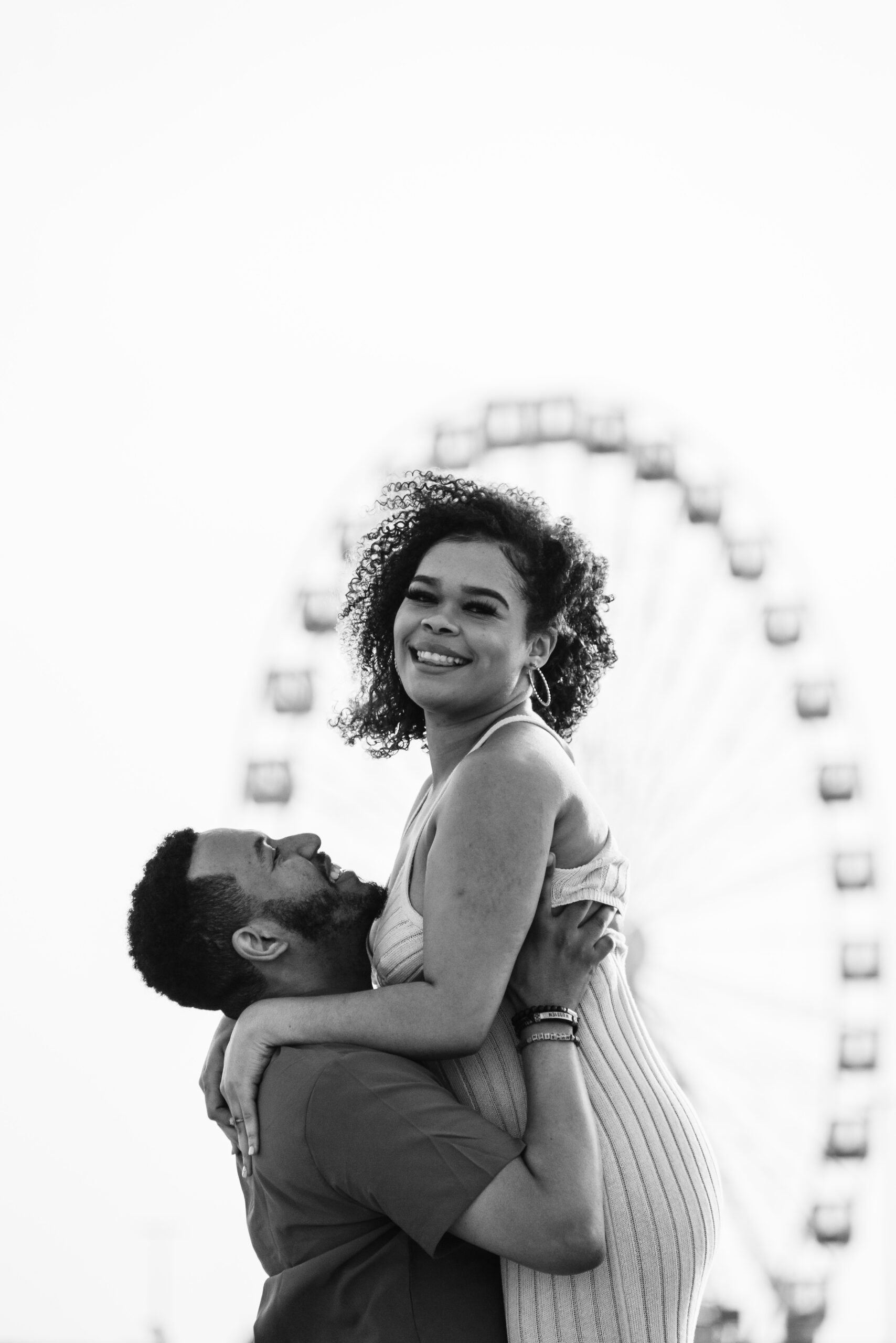 a man is hugging a woman in front of a ferris wheel
