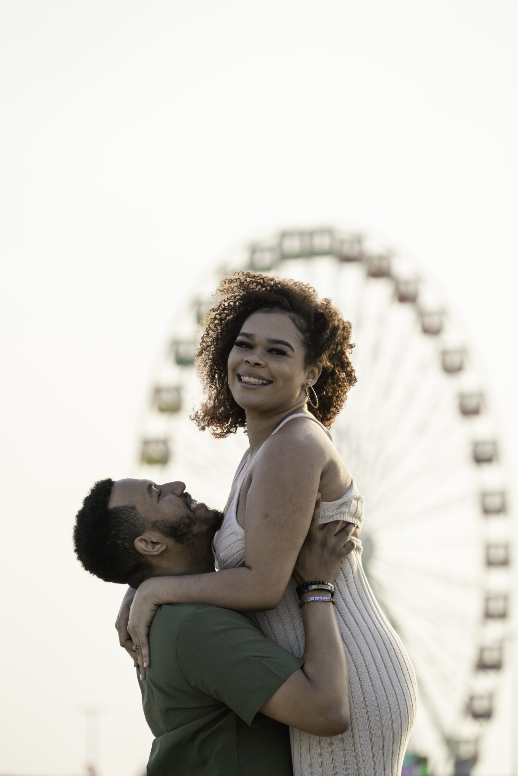 a man and woman hugging in front of a ferris wheel