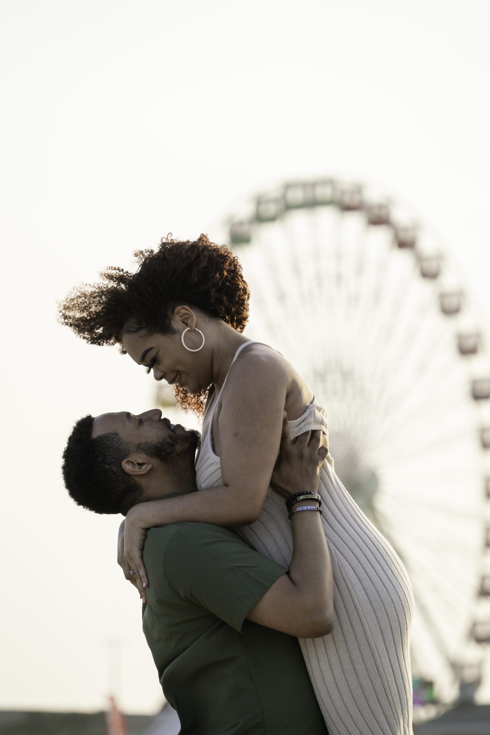 a woman holding a man in front of a ferris wheel