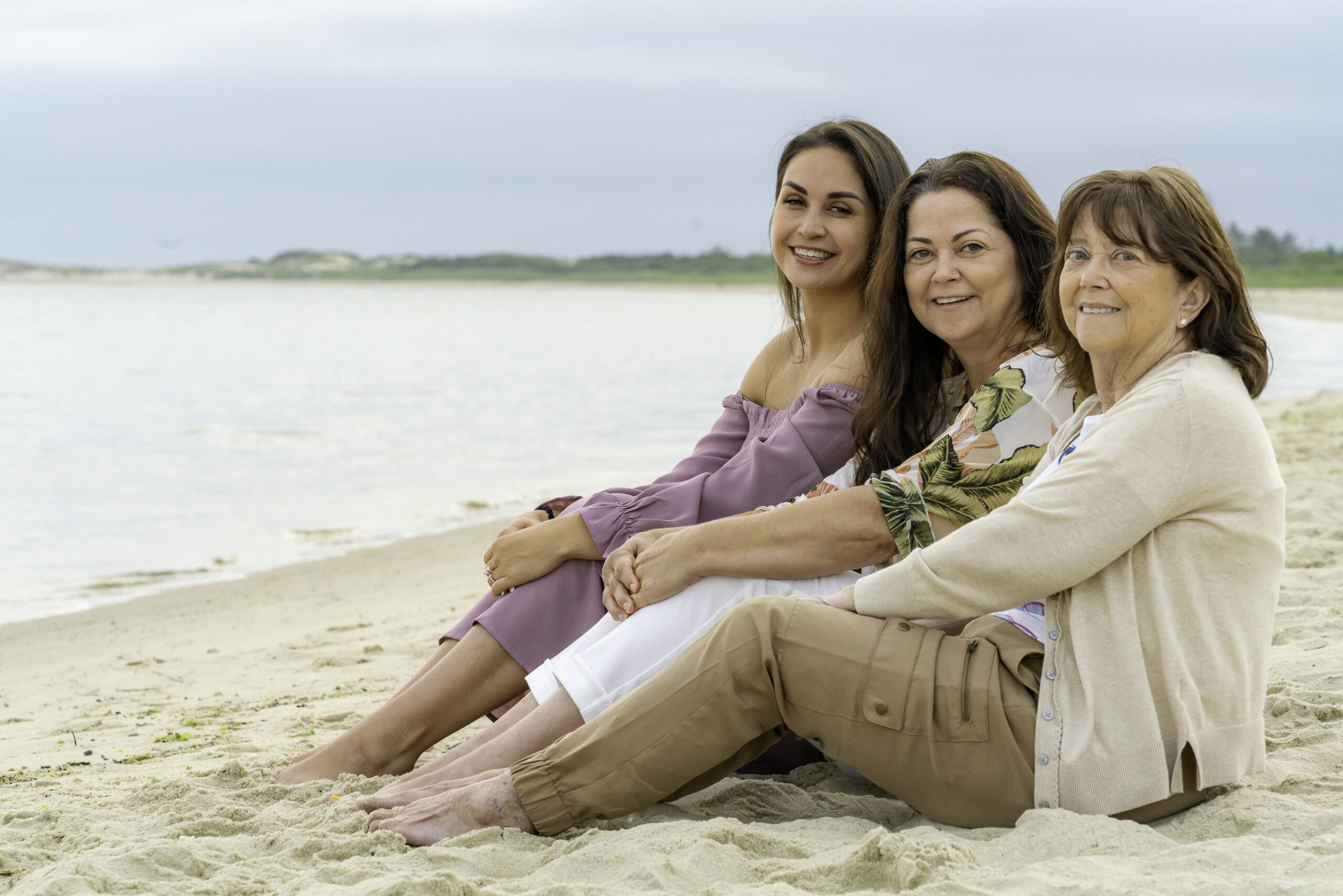 three women are sitting on the beach together