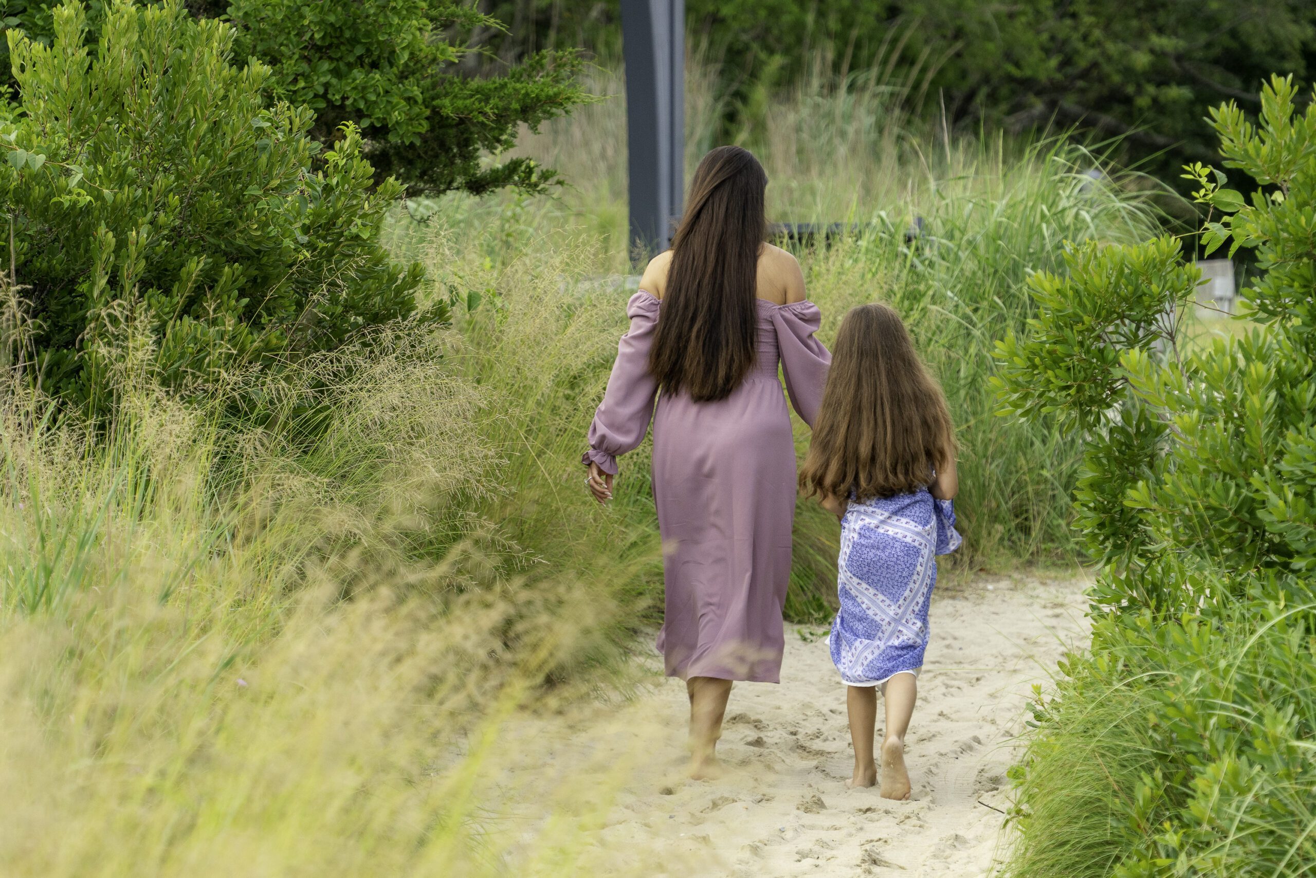 a mother and her daughter walking down a path