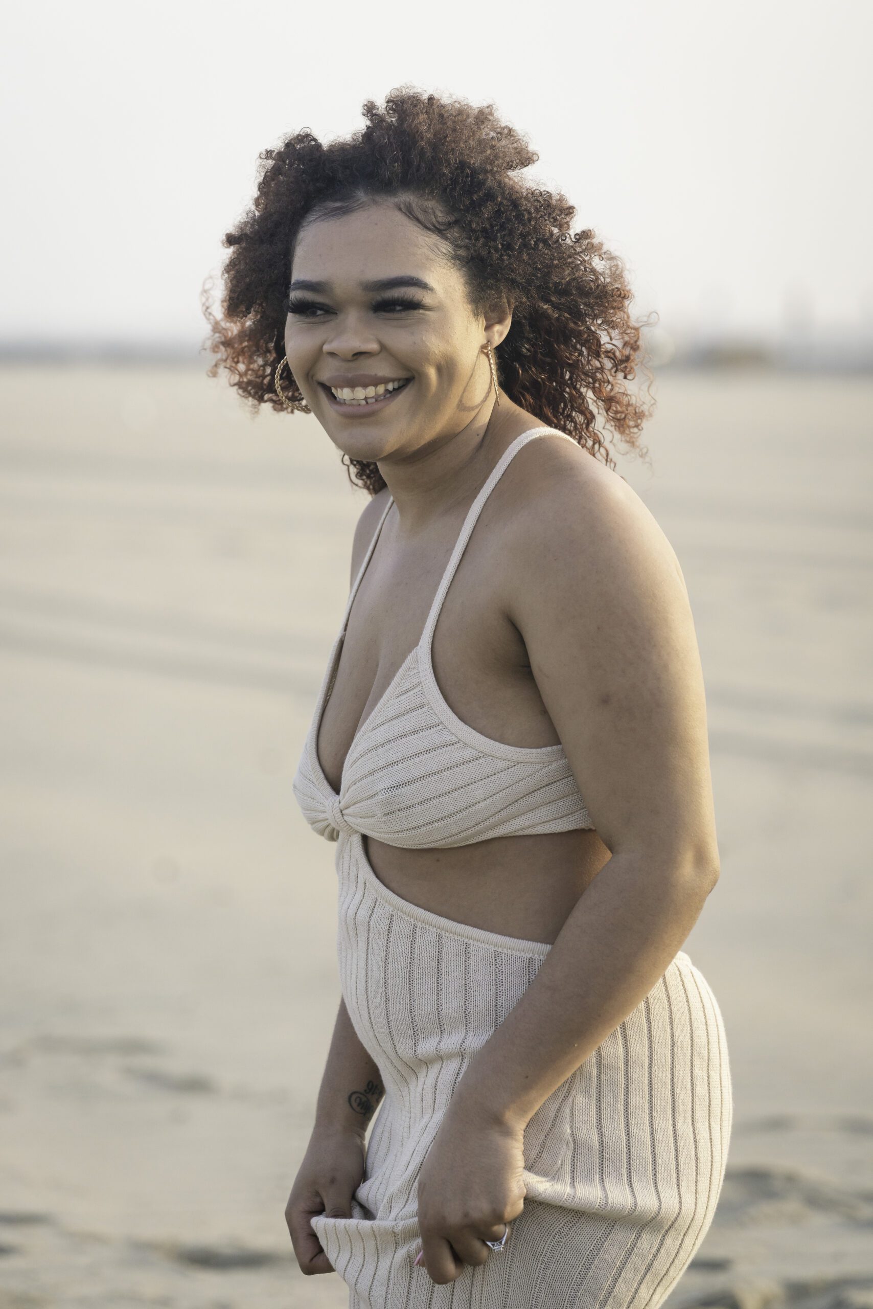 a woman standing on the beach smiling for the camera