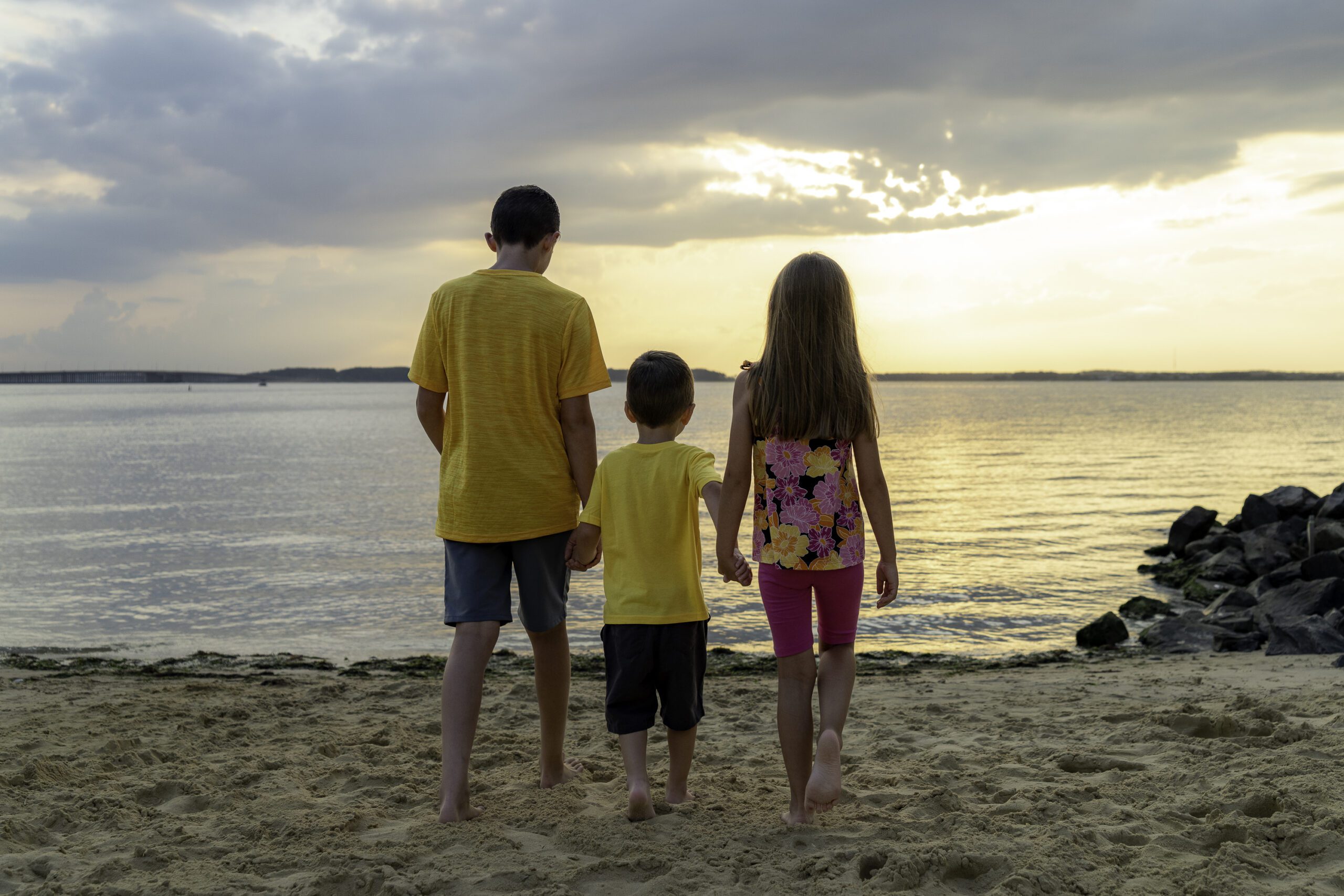 a family standing on the beach watching the sun set
