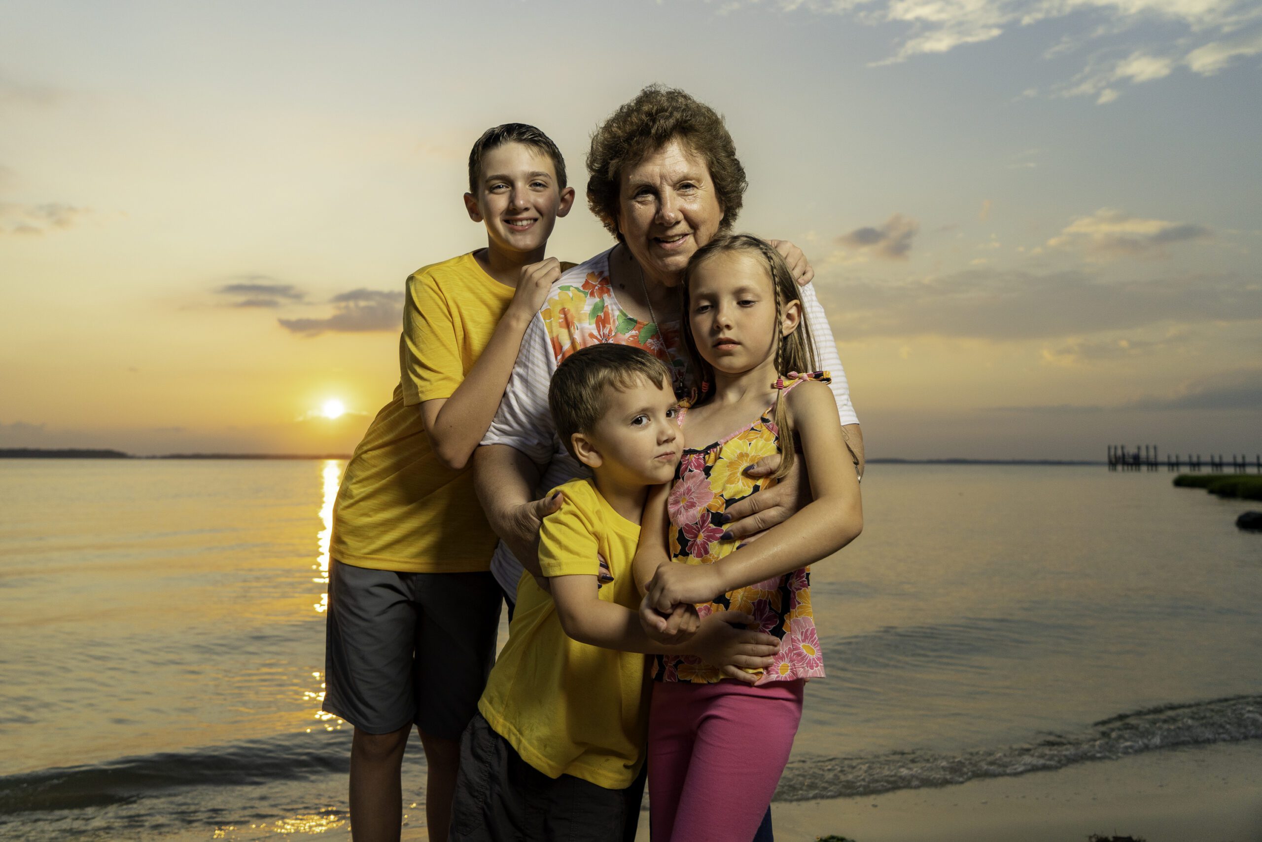 a family poses for a photo on the beach at sunset