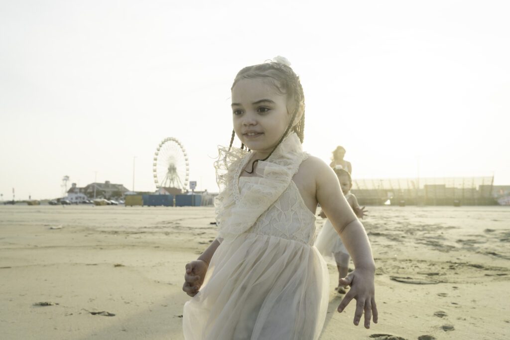 a little girl in a white dress on the beach
