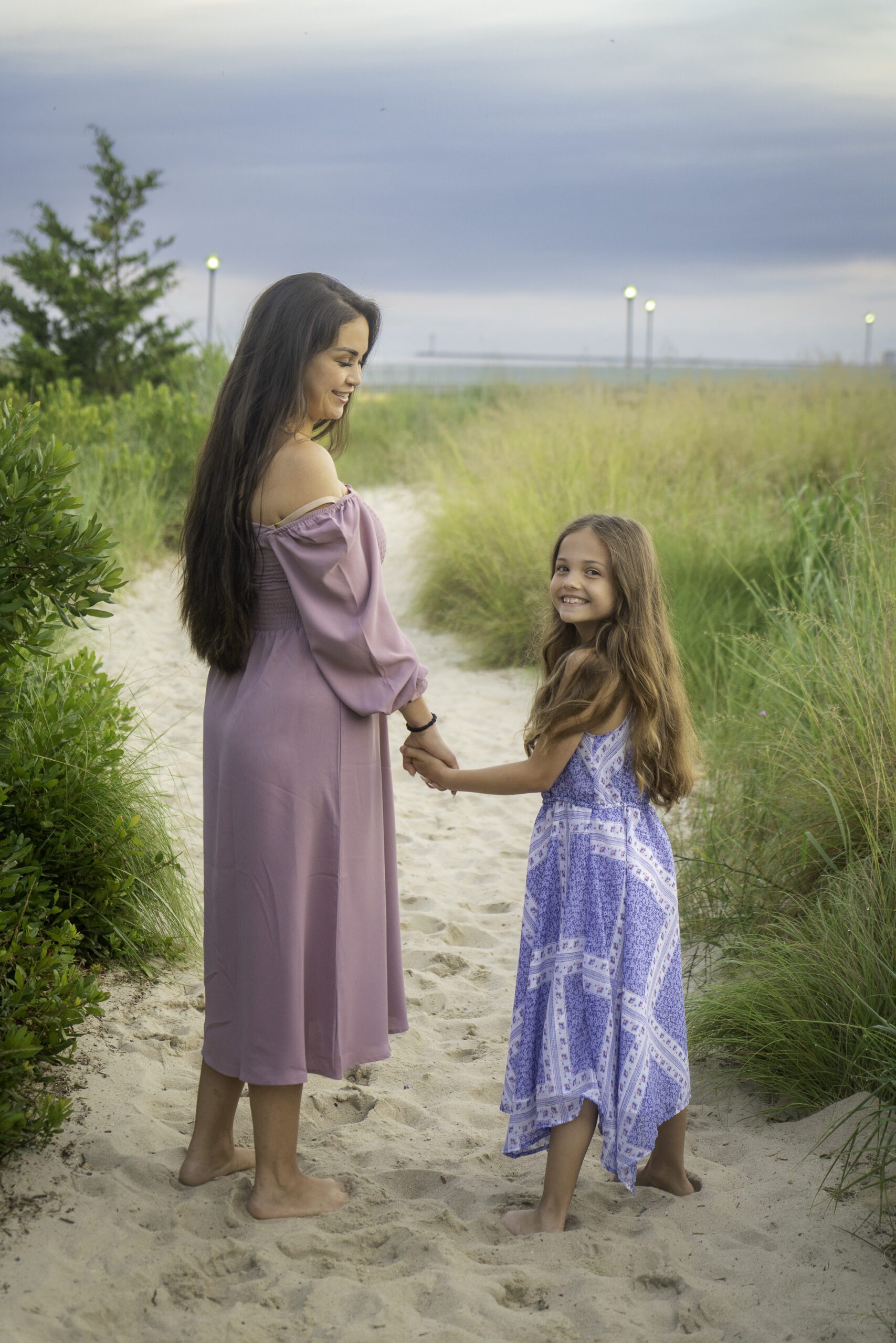 a woman holding hands with a little girl on the beach