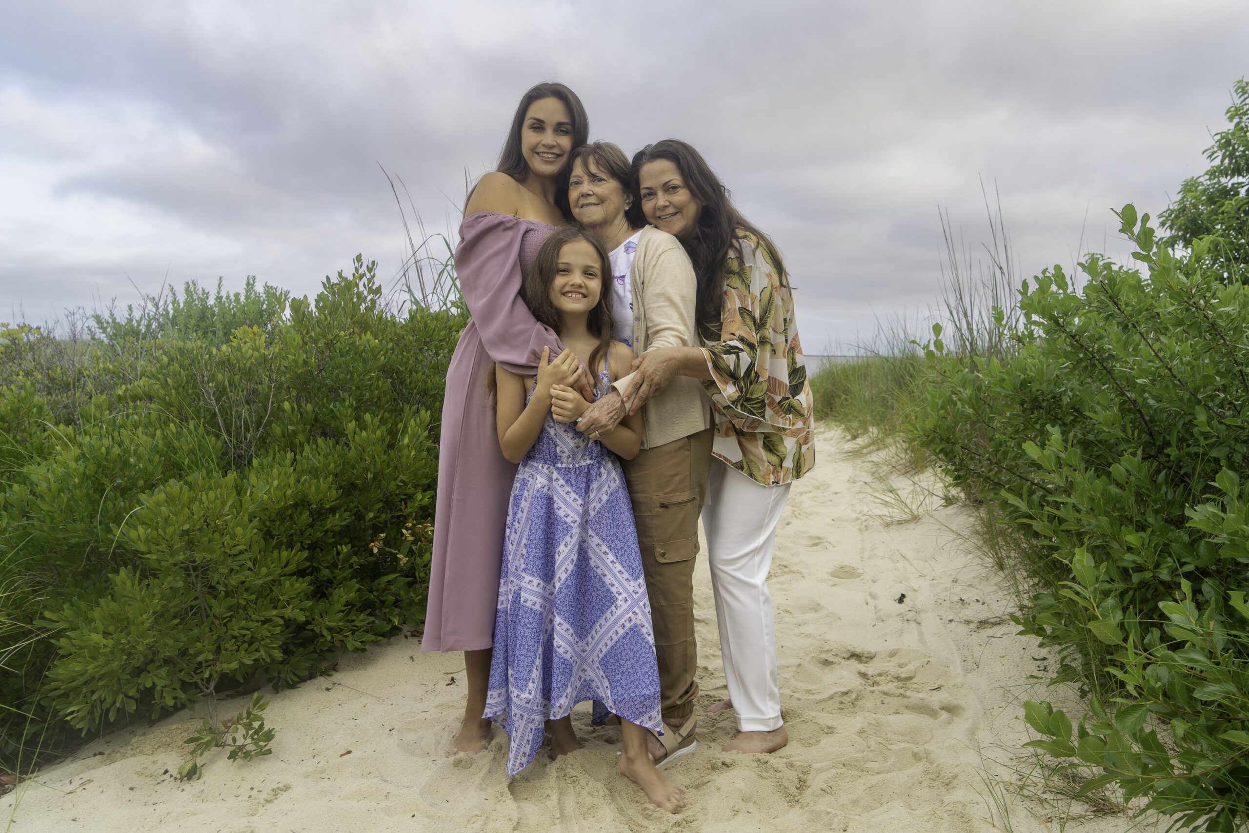 three women and a girl standing on a beach