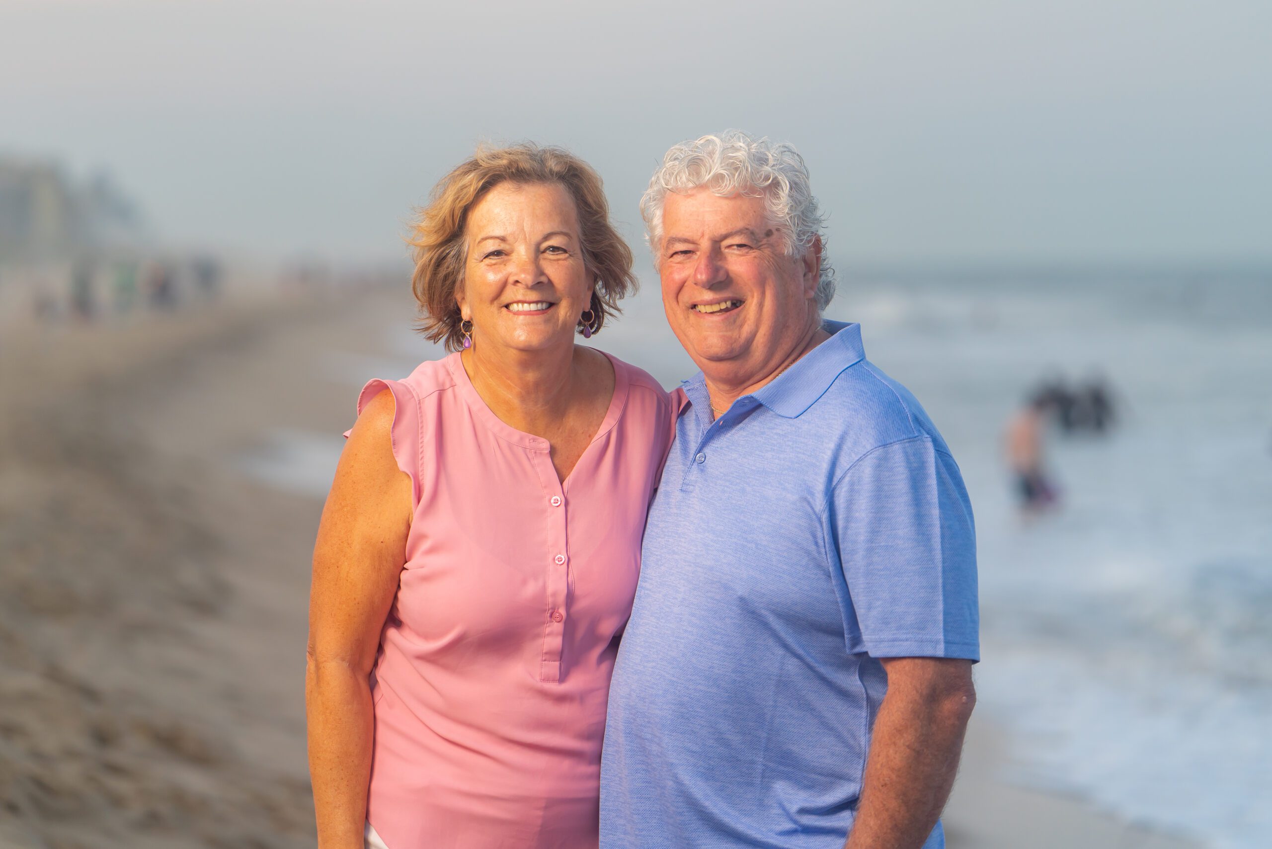 an older couple standing on the beach together