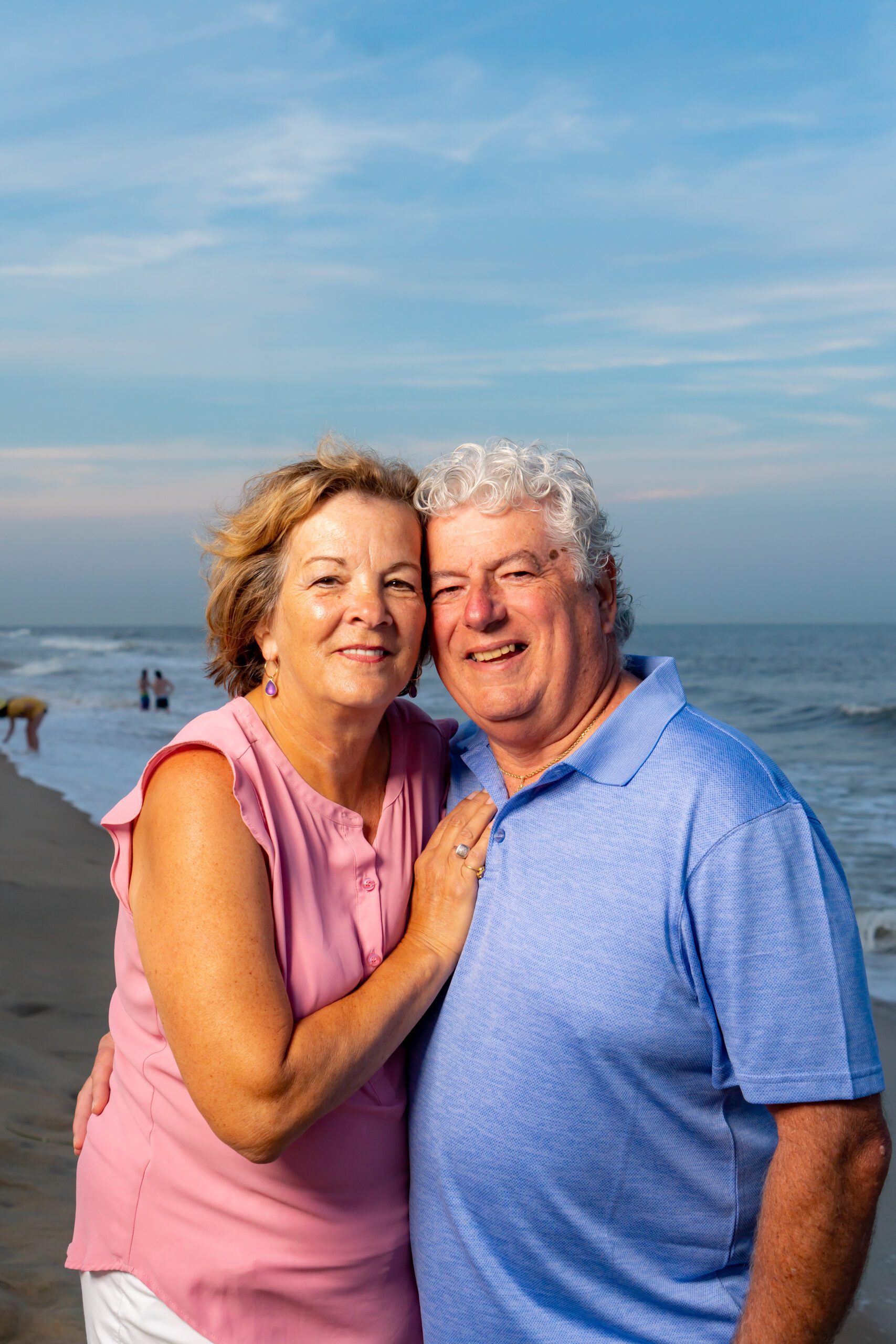 a man and woman standing next to each other on a beach