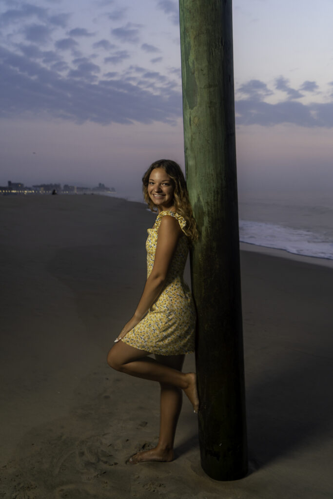 a woman posing next to a pole on the beach