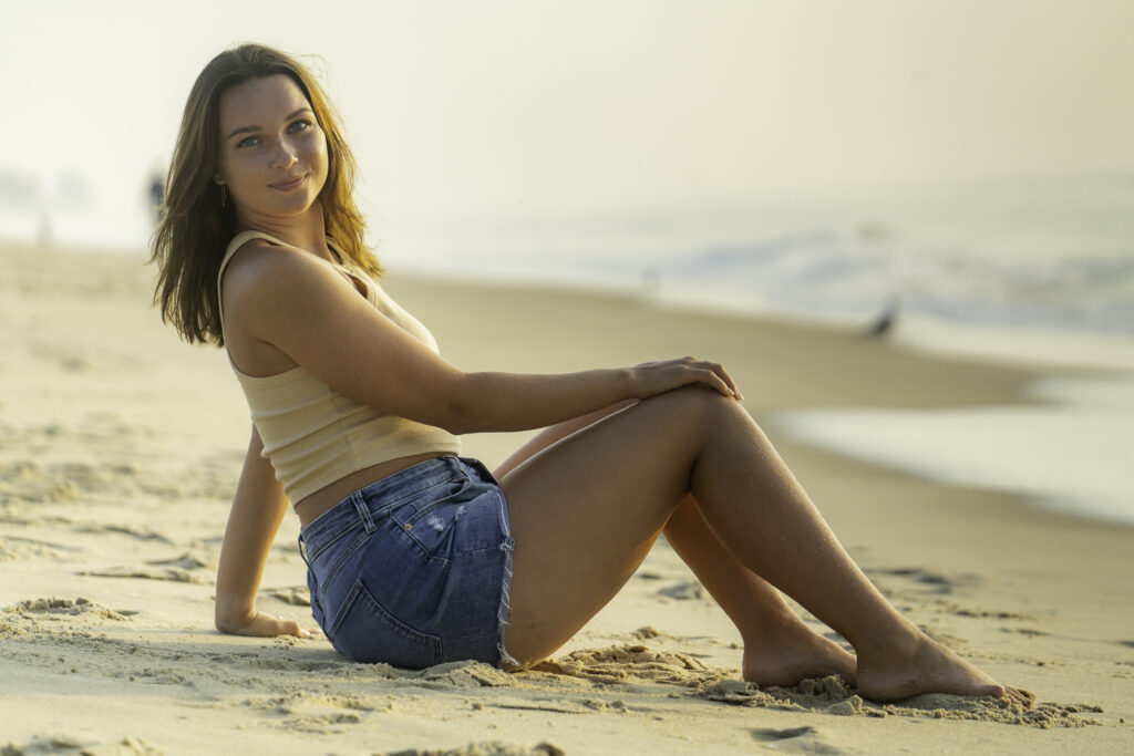 a woman is sitting on the beach with her legs crossed