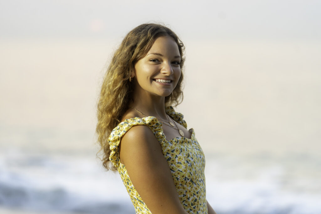 a young woman standing on the beach smiling