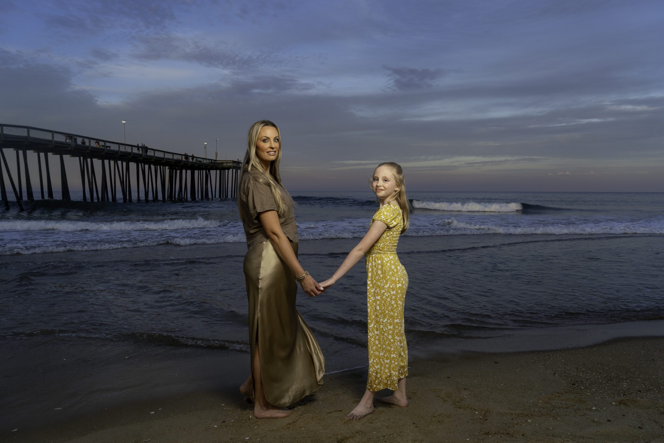two women holding hands while standing on the beach
