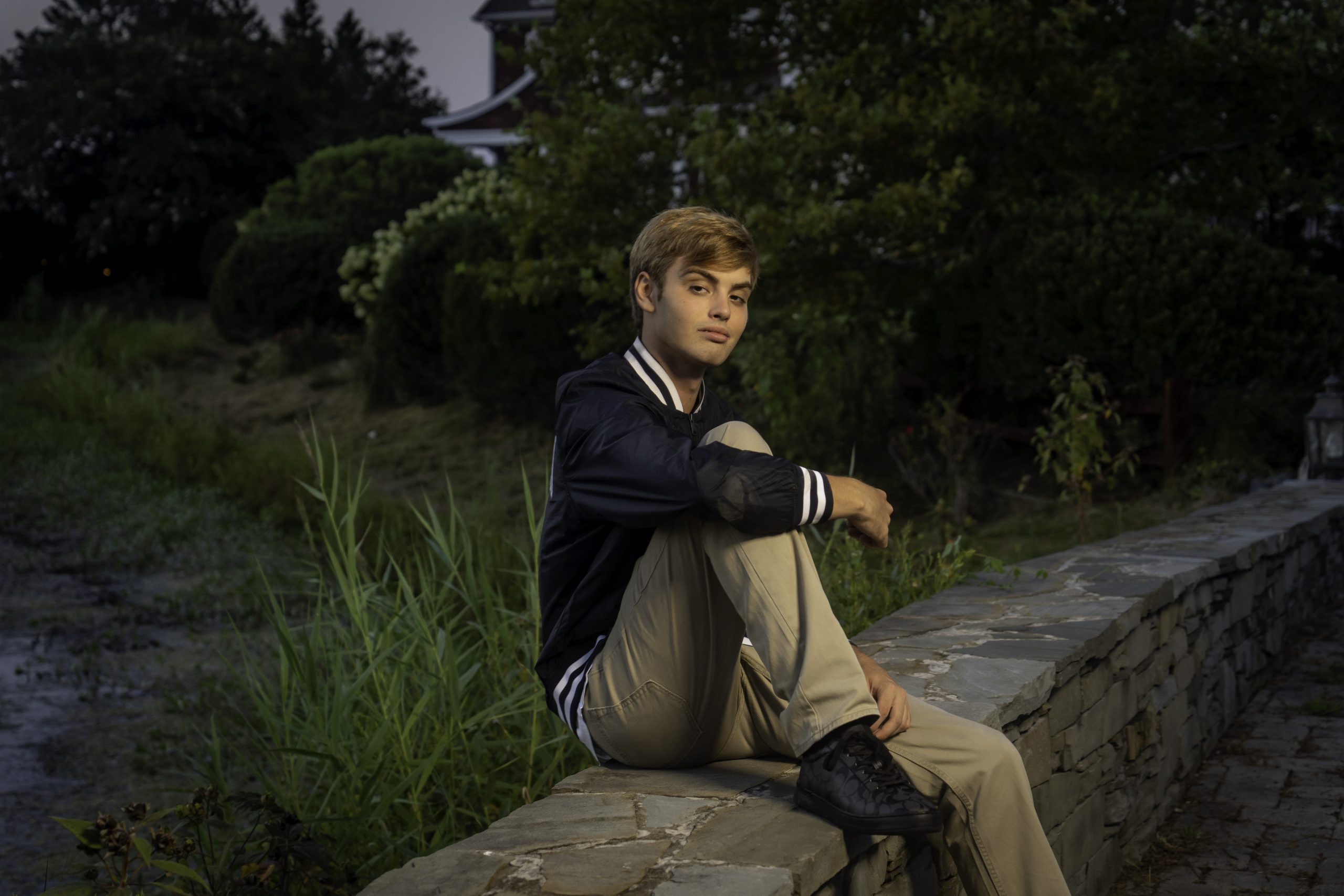 a young man sitting on top of a stone wall