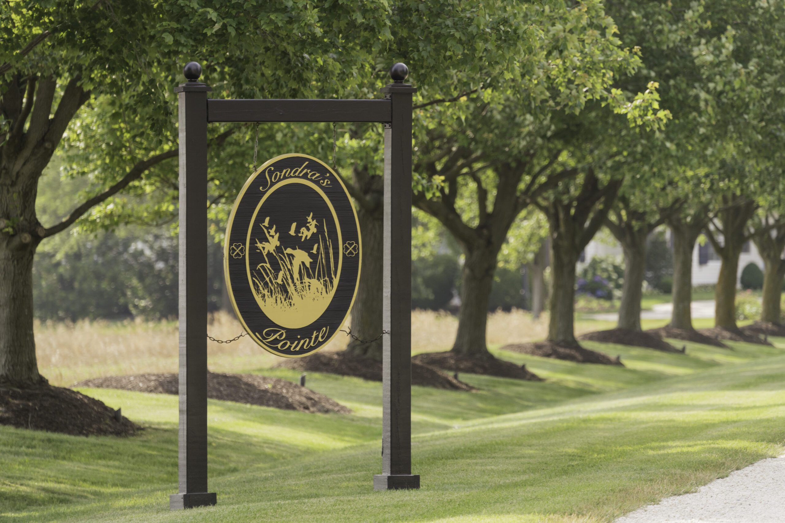 a black and gold sign in front of some trees