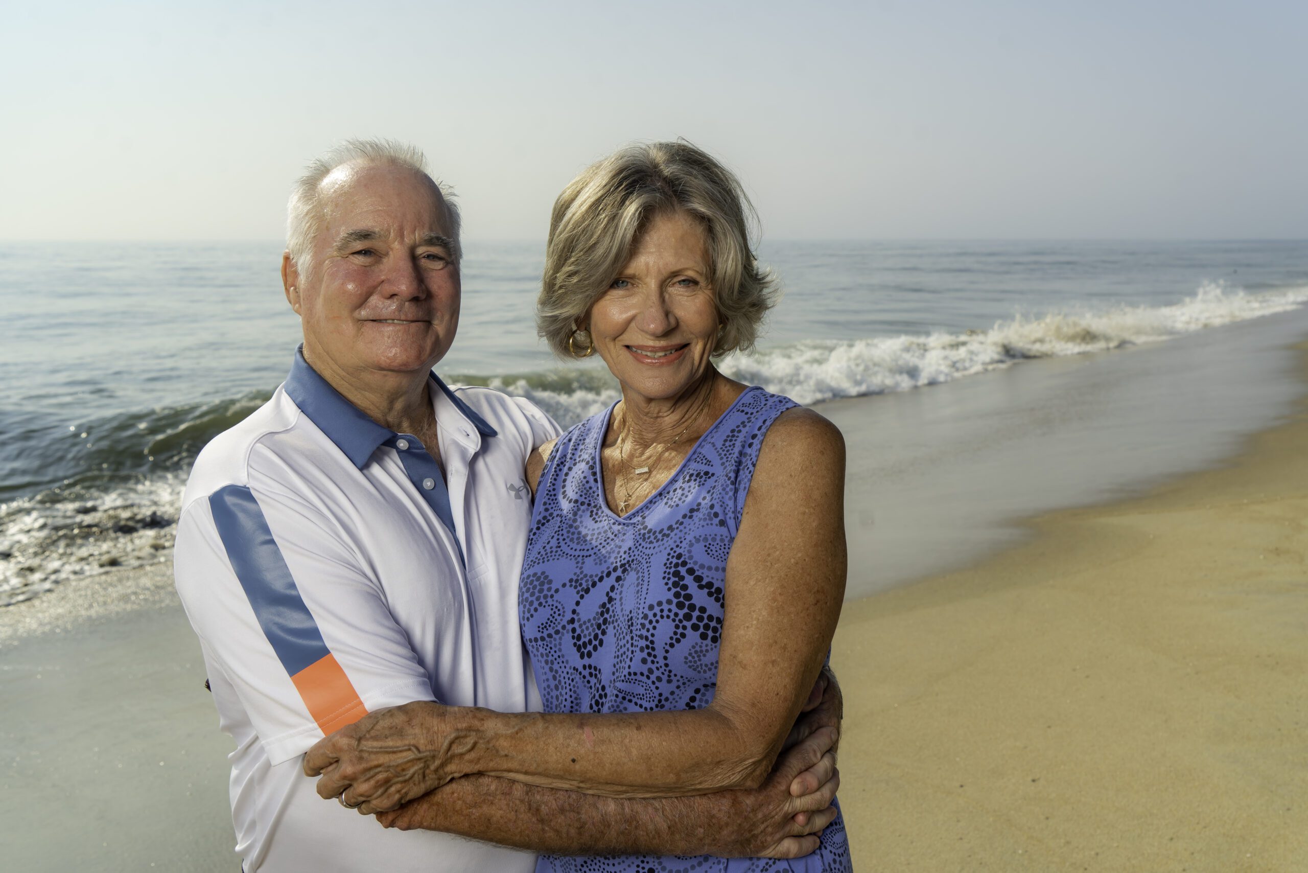 an older couple embracing on the beach