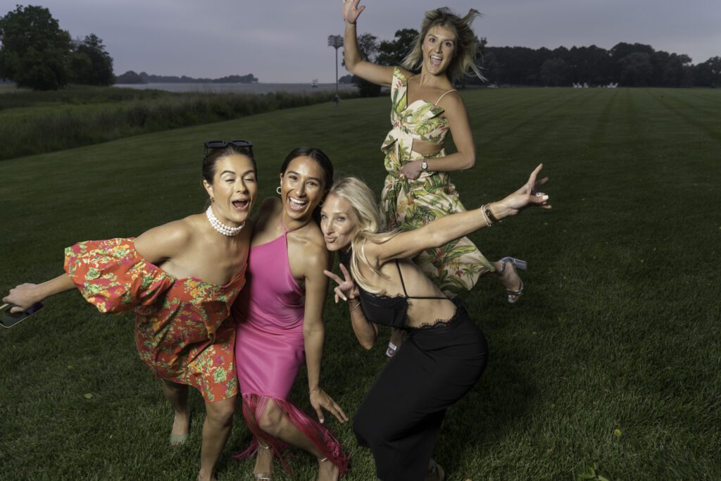 four women posing for a photo in the grass