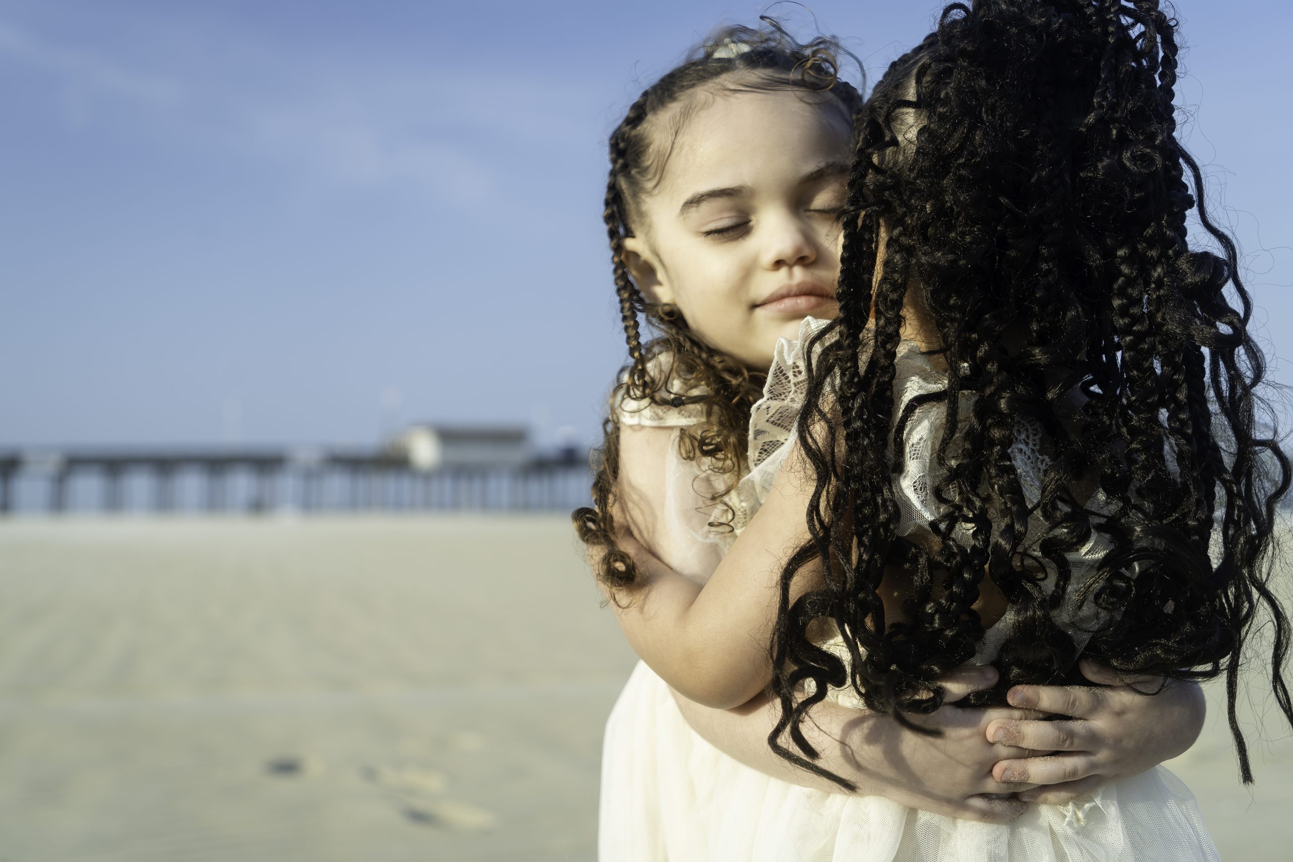 a young girl hugging her mother on the beach