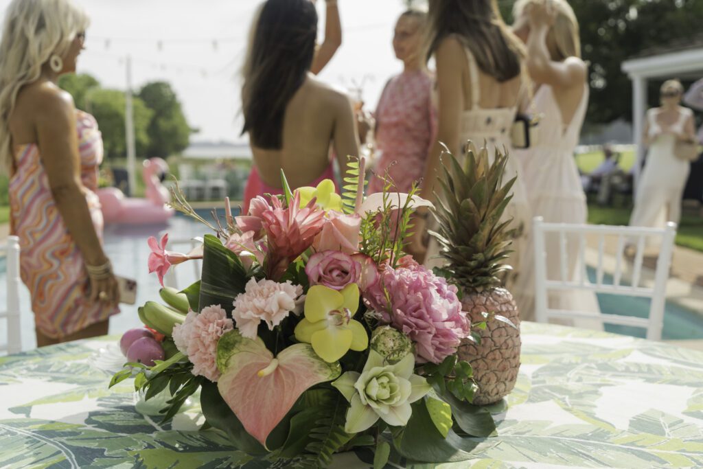 a group of women standing around a table with flowers and pineapples