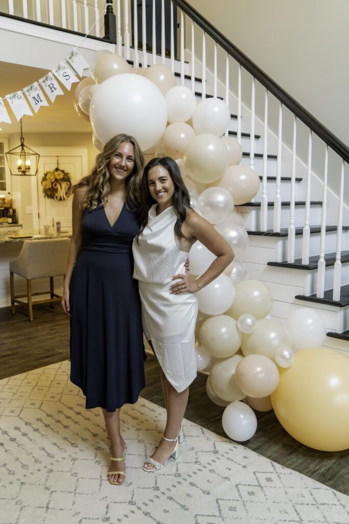 two women standing next to each other in front of balloons