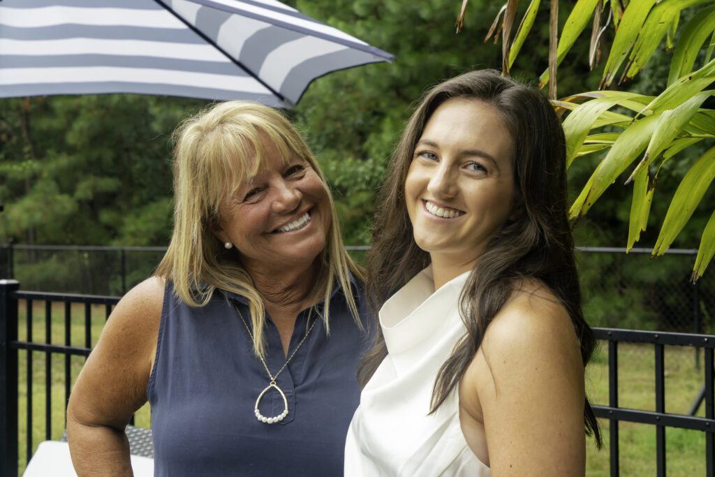 two women standing next to each other under an umbrella