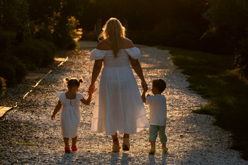 a woman and two children walking down a dirt road