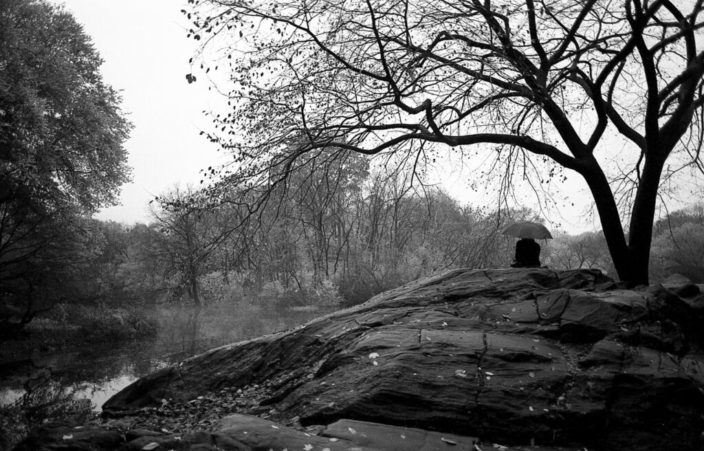 a black and white photo of a person sitting on a rock