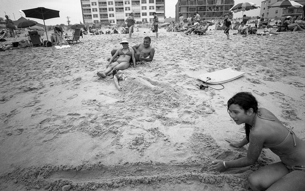 a woman sitting on the beach in front of other people