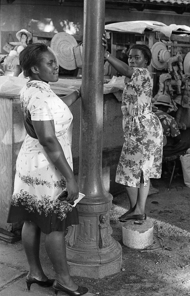 two women standing next to each other near a pole
