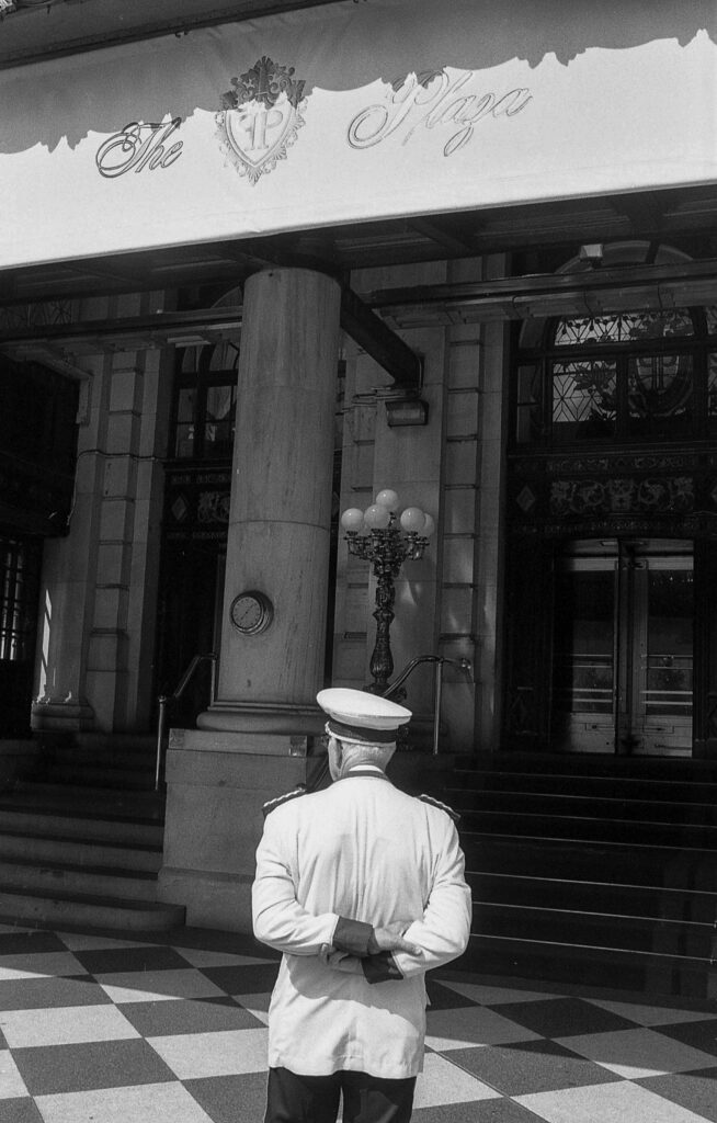 a black and white photo of a man standing in front of a building