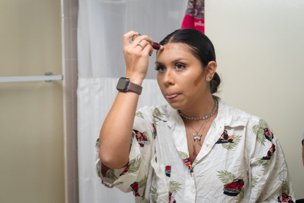 a woman in a white shirt is putting on makeup