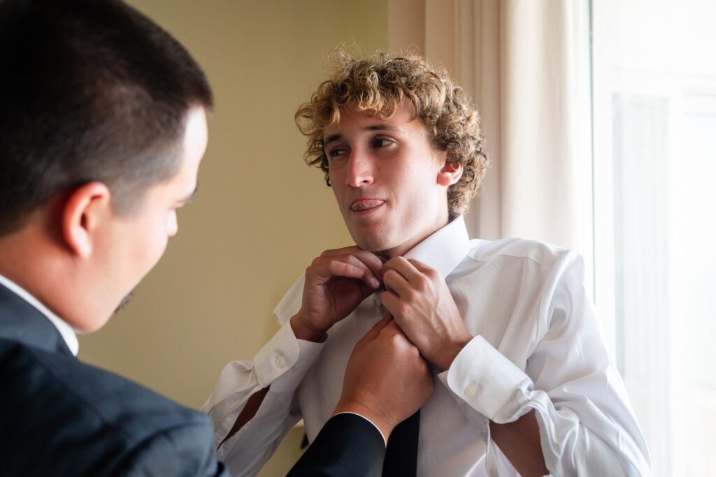 a man adjusting his tie while looking in the mirror