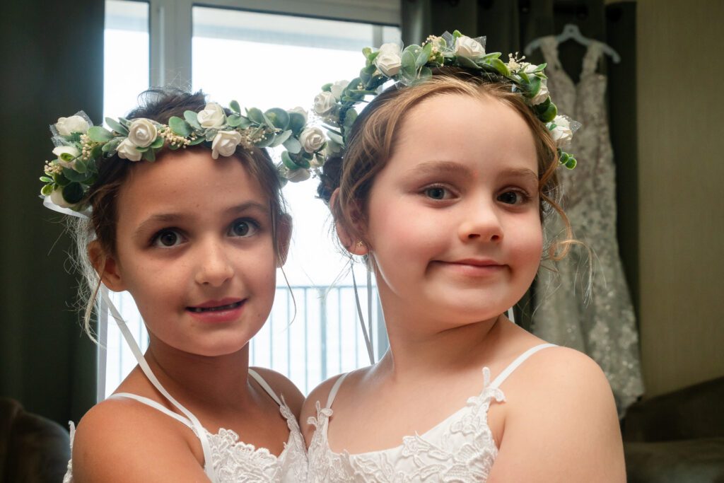 two young girls wearing flower crowns in front of a window
