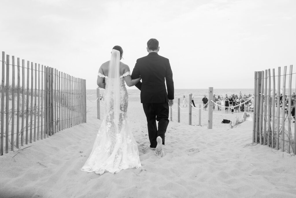 a bride and groom walking down the beach