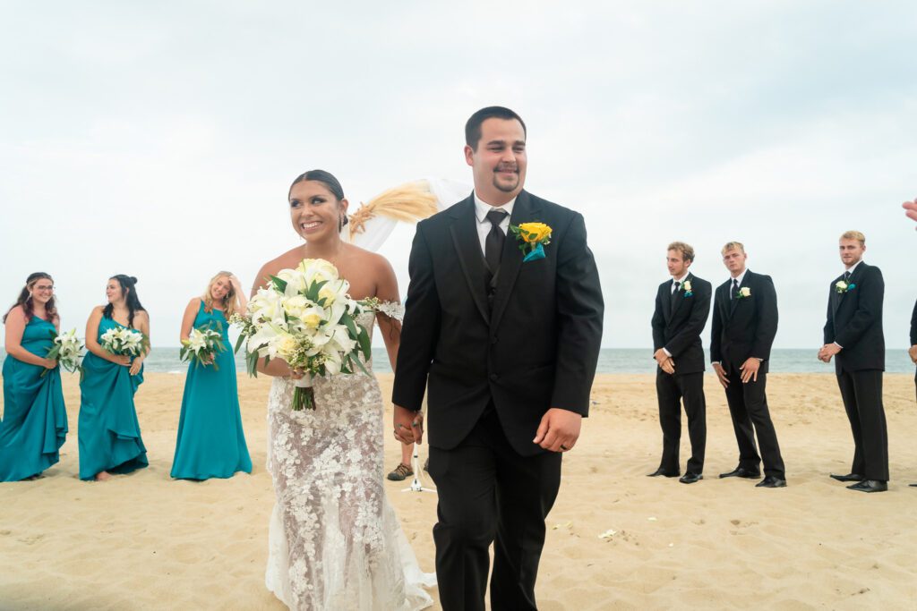 a bride and groom walking on the beach