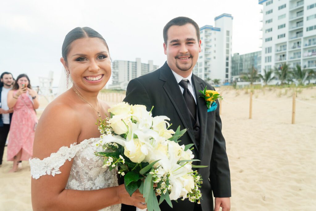 a bride and groom posing for a photo on the beach