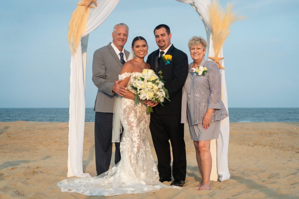 a bride and groom posing for a photo with their parents
