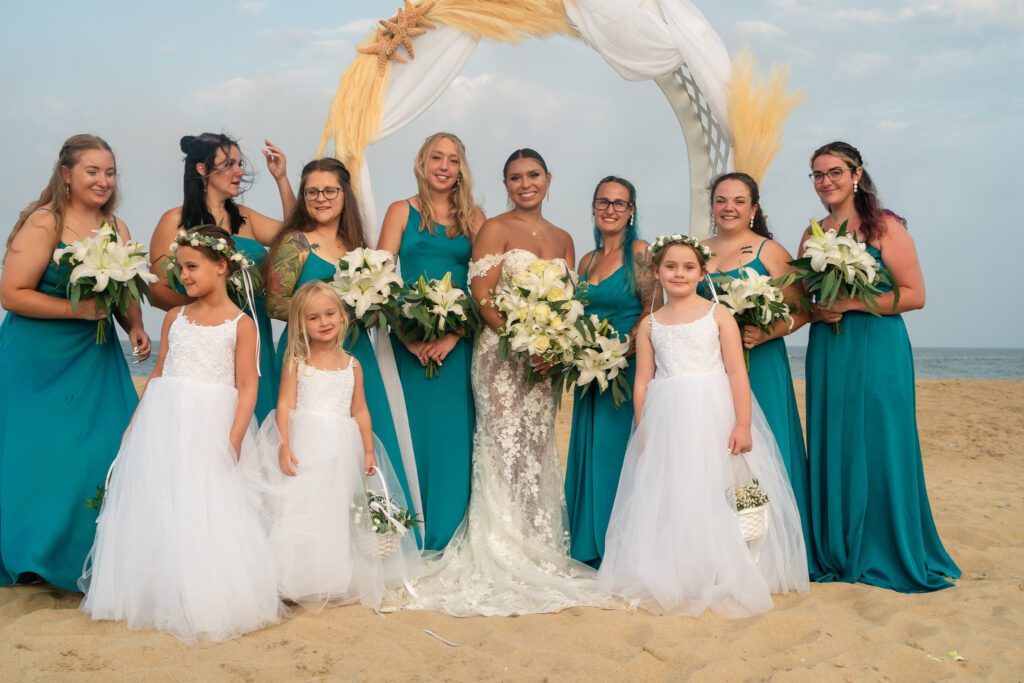 a group of bridesmaids pose for a photo on the beach