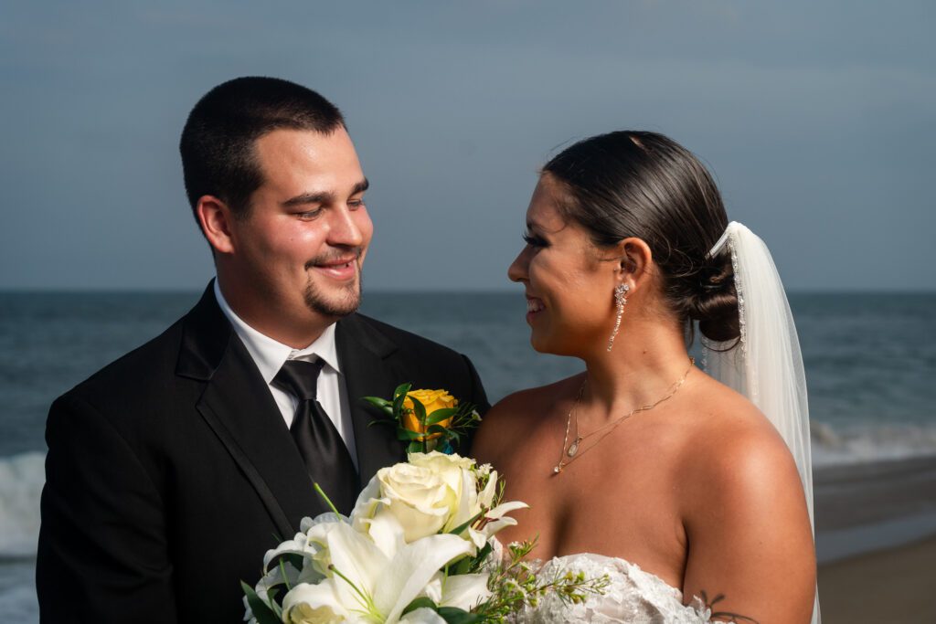 a bride and groom standing on the beach