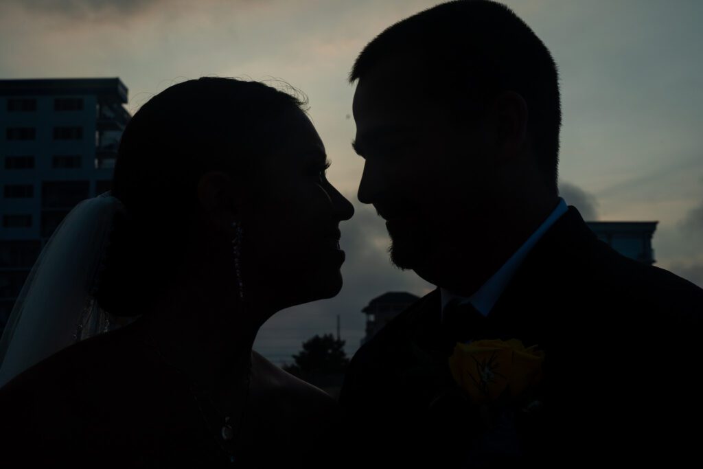 a bride and groom are silhouetted against the evening sky