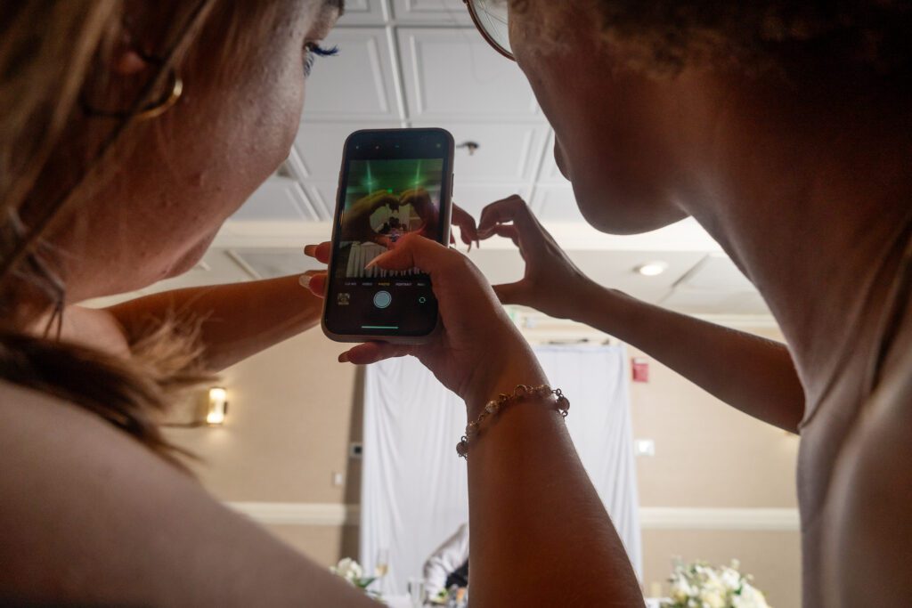 two women are taking pictures with their cell phones