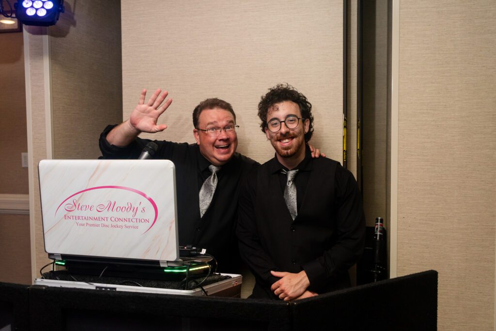 two men are posing for a picture in front of a laptop