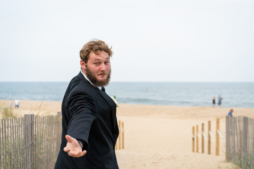 a man in a tuxedo pointing at the beach