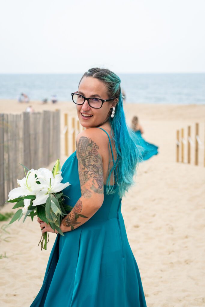 a woman with blue hair and glasses holding a bouquet of flowers