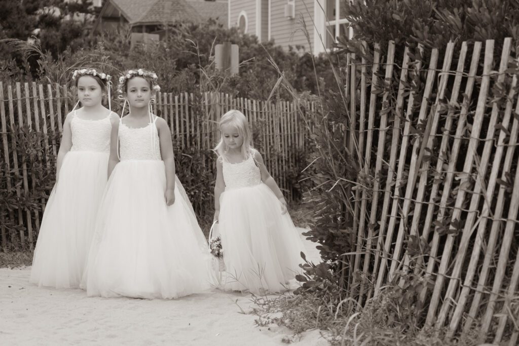 three young girls in dresses standing next to a fence