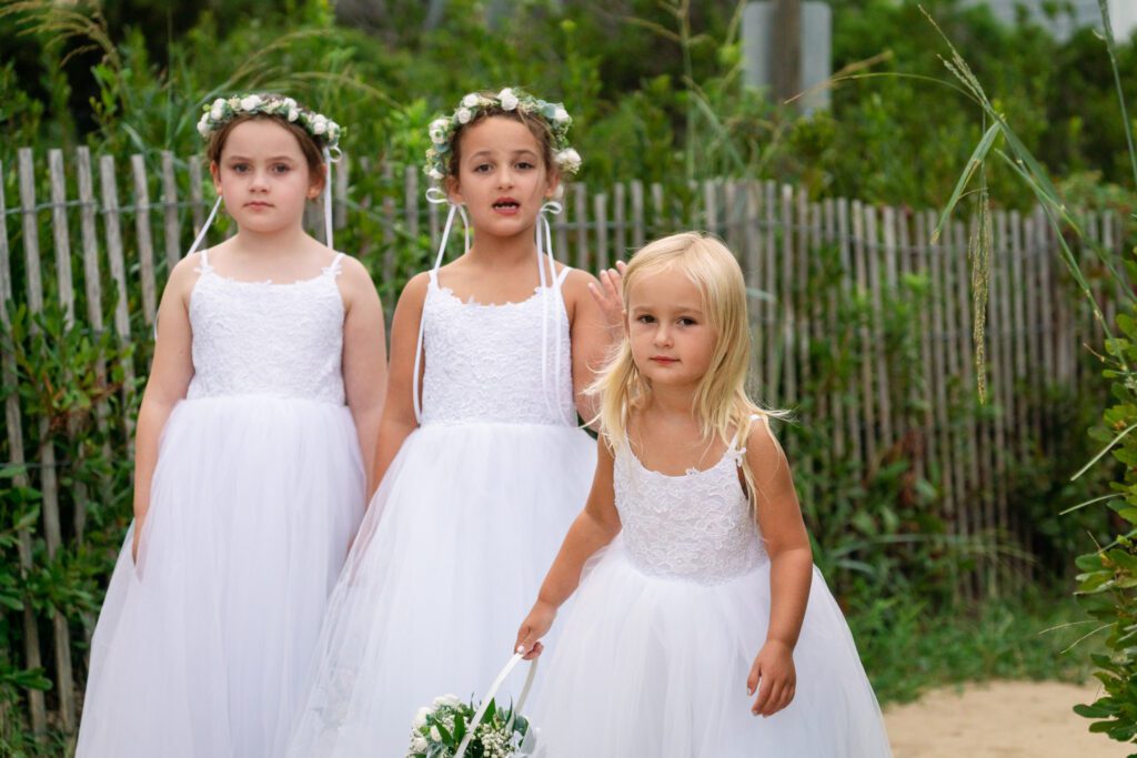 three little girls dressed in white dresses and flower crowns