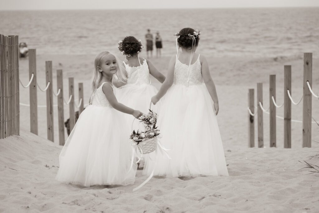 two little girls in white dresses standing on the beach